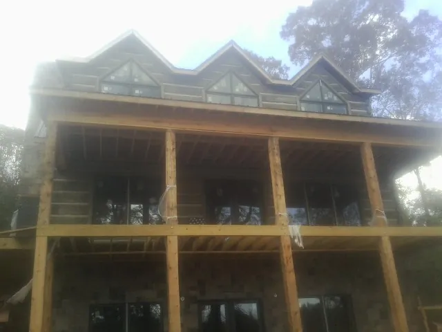 Dormers and porch framing on a large log home under construction — Roof Coating work by our crew in Hawley
