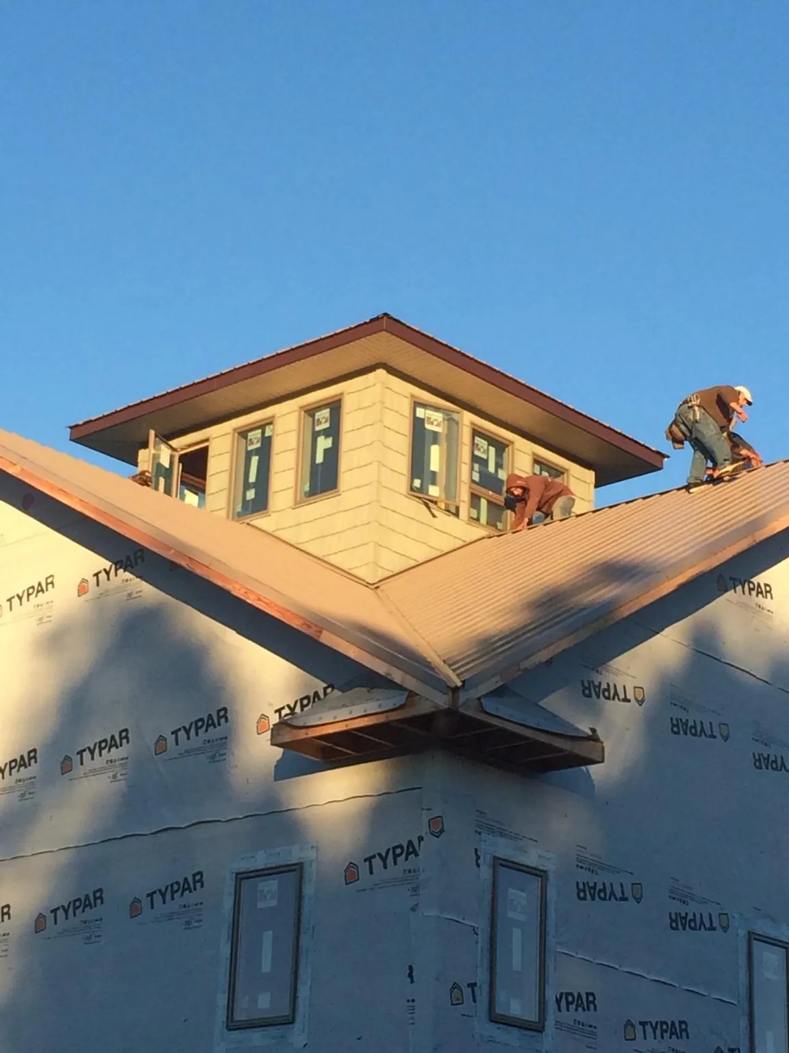 Roofers working around a rooftop cupola on a new metal roof at sunset — Roof Waterproofing in Hawley by Roofing Brothers